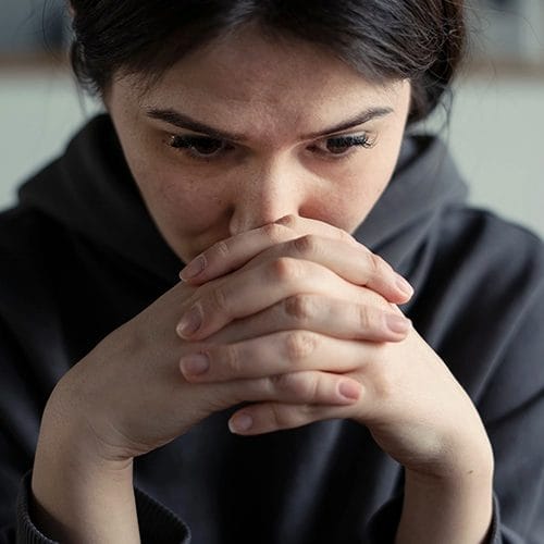 Frau mit gefaltenen Händen und in Angst