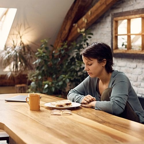 Frau ohne Appetit am Tisch schaut frustriert auf ihr Essen