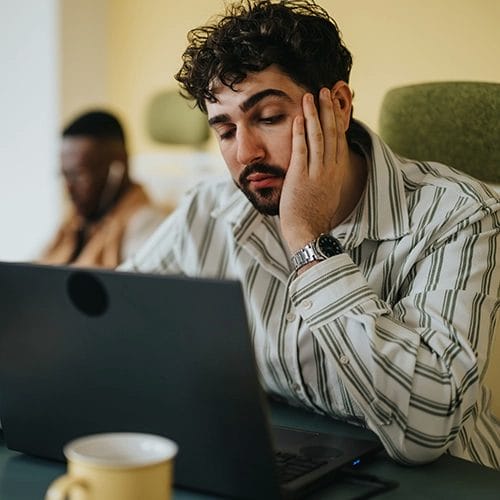 Mann sitzt erschöpft und verzweifelt vor seinem Laptop